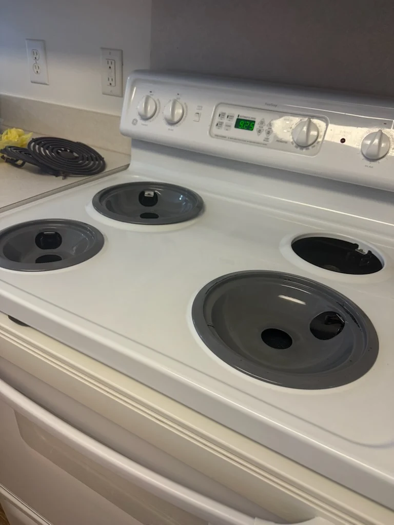 Same electric stovetop with clean drip pans and wiped surface after cleaning by Spotless Cleaning Services in Monroe, NC